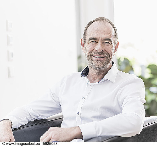 Portrait Of Smiling Mature Man Sitting In Armchair Portrait Of Smiling