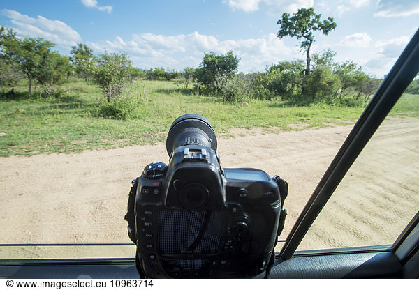 'A camera propped on the window of a vehicle pointing out into Kruger National Park; South Africa'