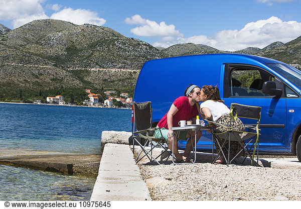 'A couple shares a kiss outside their camper van at a beach along the coast; Slano  Croatia'