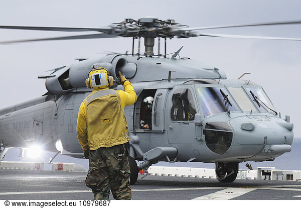'A crewman onboard the U.S.S. Peleliu (LHA-5) gives thumbs up to a MH-60S Knighthawk helicopter after landing; Hawaii  United States of America'