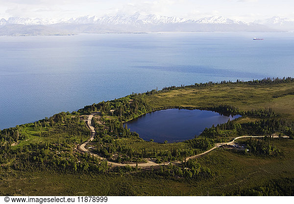 'A lake and winding road off Kachemak Bay with a view of the Kenai Mountains  Kachemak Bay State Park; Homer  Alaska  United States of America'