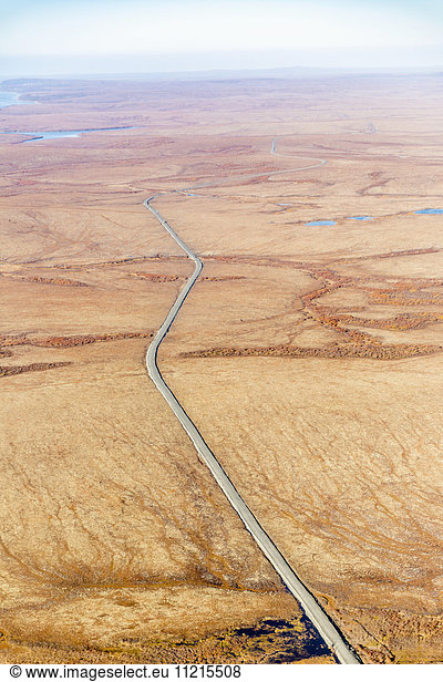 'Aerial view of autumn coloured tundra surrounding the gravel road which connects St. Mary's to Mountain Village  Yukon Delta  Arctic Alaska; Saint Mary's  Alaska  United States of America'