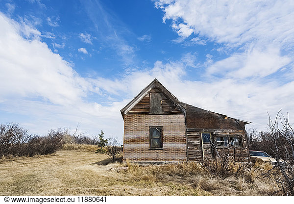 'An old  abandoned wooden house and vintage car on the prairies; Alberta  Canada'