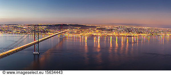 25. April Brücke über den Tejo vor beleuchteter Stadtlandschaft in der Abenddämmerung  Lissabon  Portugal