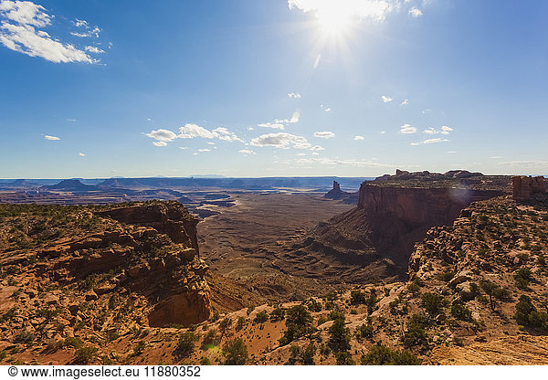 'Arid landscape of cliffs and rugged terrain under a blue sky with cloud and sunlight; Utah  United States of America'
