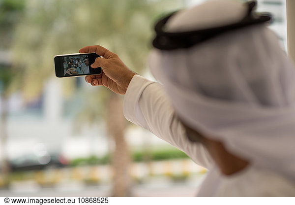 Über die Schulter eines Mannes aus dem Nahen Osten  der mit Freunden in einem Cafe ein Smartphone mitnimmt  Dubai  Vereinigte Arabische Emirate