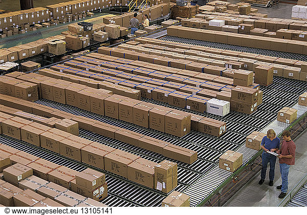 Überblick über ein großes industrielles Vertriebslager  in dem Produkte in Kartons auf Förderbändern und Regalen gelagert werden.