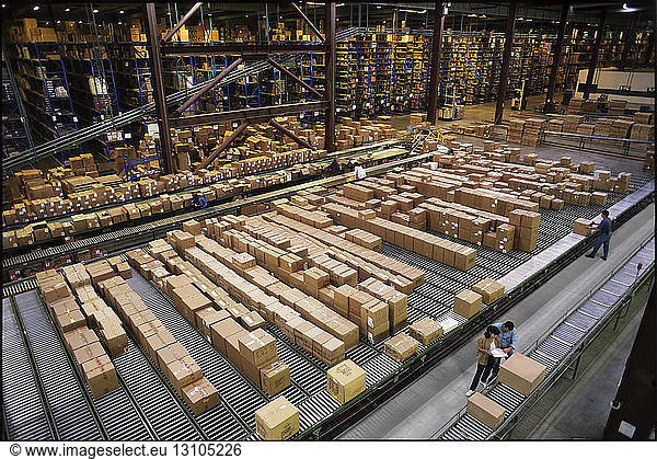 Überblick über ein großes industrielles Vertriebslager  in dem Produkte in Kartons auf Förderbändern und Regalen gelagert werden.