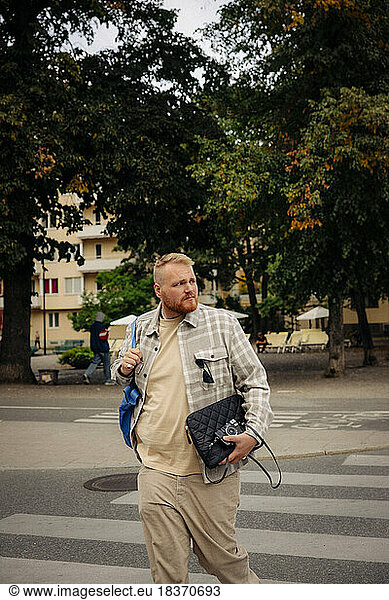 Übergewichtiger Mann schaut beim Überqueren der Straße in der Stadt weg