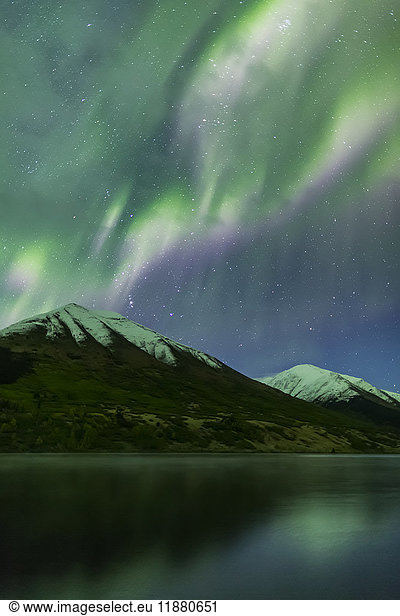 'Bright green aurora borealis dances over the Kenai Mountains  Summit Lake reflects the skies in the foreground  Moose Pass  Kenai Peninsula  South-central Alaska; Alaska  United States of America'