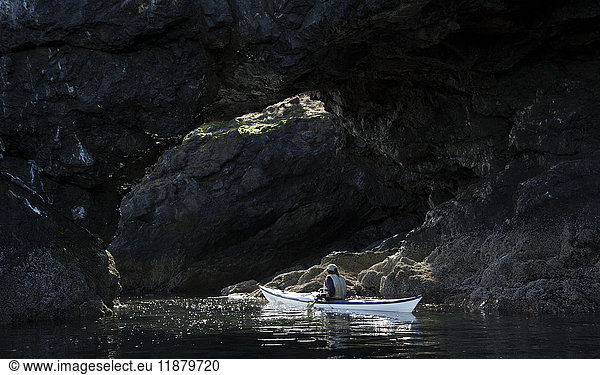 'Canoeing along dark rocks of the shoreline in Kachemak Bay State Park; Alaska  United States of America'