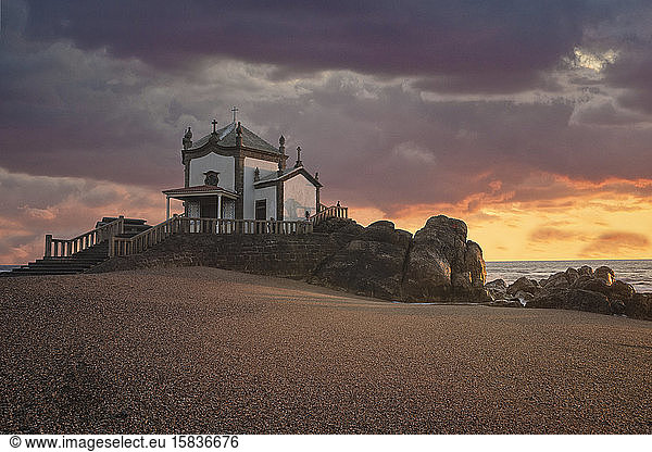 'Capela do Senhor da Pedra' at sunset over Atlantic Ocean