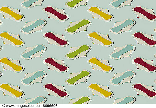 3D pattern of colorful sanitary pads flat laid against green background