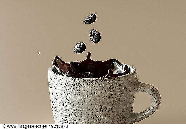 3D render of coffee beans falling into mug of coffee