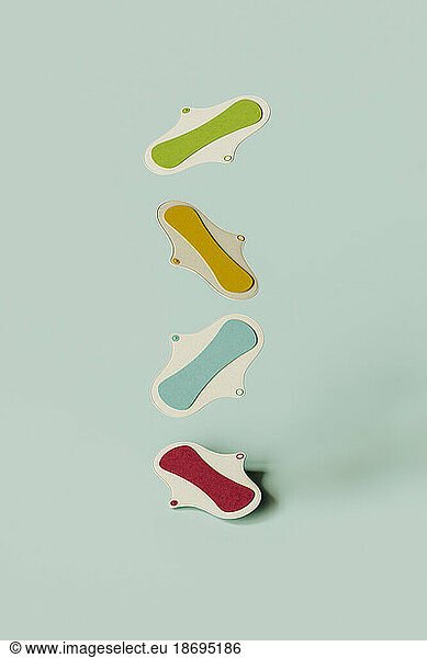 3D render of colorful sanitary pads falling against green background