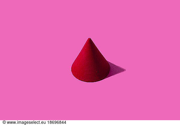 3D render of red cone against pink background