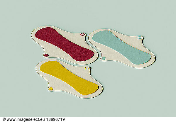 3D render of yellow  red and green sanitary pad flat laid against green background