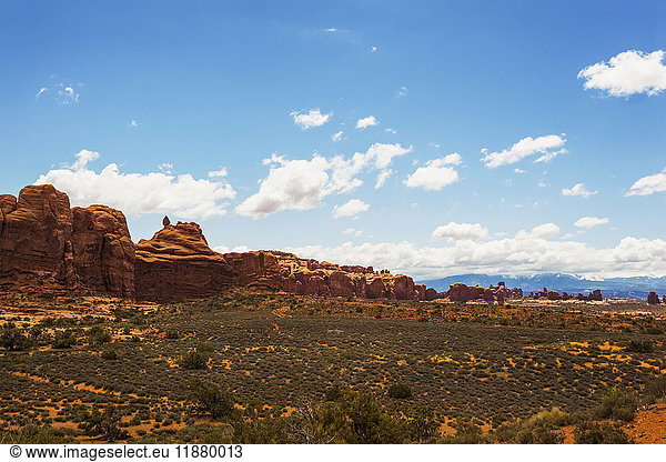 'Desert landscape of rugged rock formations under a blue sky with cloud  Arches National Park; Utah  United States of America'