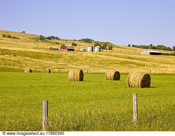 'Farmland with farm structures and hay bales on rolling hills; Cochrane  Alberta  Canada'