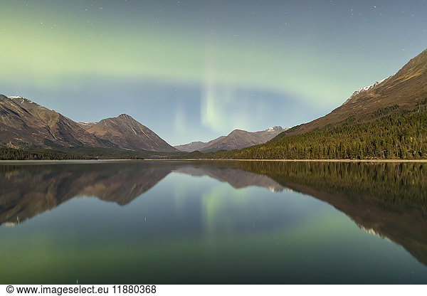'Green Aurora Borealis dances over the Kenai Mountains  Upper Trail Lake reflections the skies in the foreground  Kenai Peninsula  Moose Pass  South-central Alaska; Alaska  United States of America'