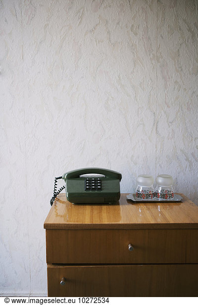 'Hotel nightstand with push-button phone and water glasses  textured wallpaper; Kiev  Ukraine'