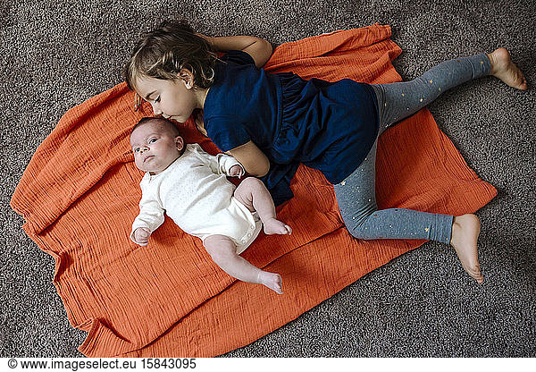 4 Jahre alt auf dem Boden mit Kleinkind auf orangefarbener Decke