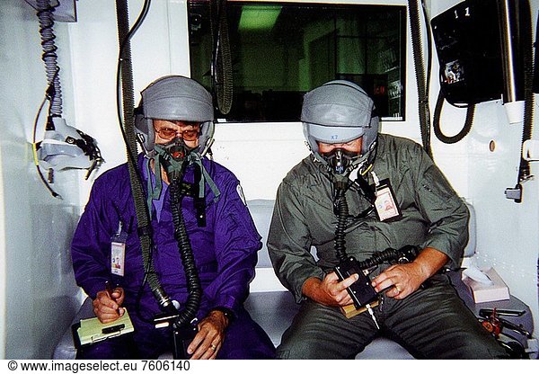 10/01/2000 ___ Jan Zysko left and Rich Mizell right test a Personal Cabin Pressure Altitude Monitor in an altitude chamber at Tyndall Air Force Base in Florida. Zysko invented the pager_sized monitor that alerts wearers of a potentially dangerous or deteriorating cabin pressure altitude condition  which can lead to life_threatening hypoxia. Zysko is chief of the KSC Spaceport Engineering and Technology directorate´s data and electronic systems branch. Mizell is a Shuttle processing engineer. The monitor  which has drawn the interest of such organizations as the Federal Aviation Administration for use in commercial airliners and private aircraft  was originally designed to offer Space Shuttle and Space Station crew members added independent notification about any depressurization
