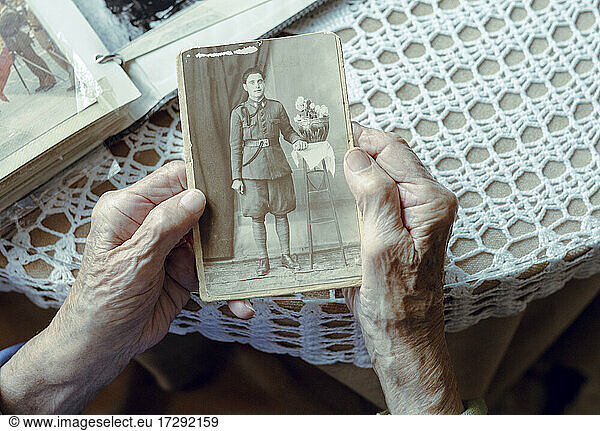 Ältere Frau erinnert sich an ihre Vergangenheit  während sie ein altes Foto zu Hause betrachtet