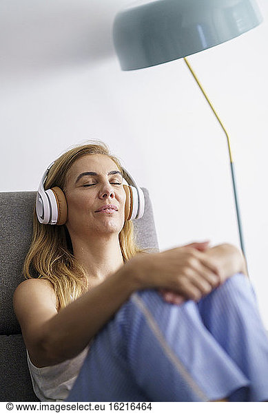 Ältere Frau hört zu Hause Musik über Kopfhörer