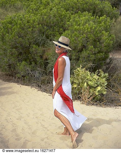 Ältere Frau im weißen Anzug genießt einen Nachmittag am Strand von Islantilla  Huelva