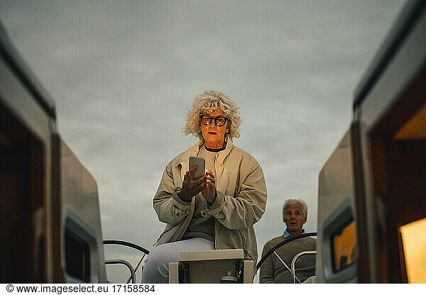 Ältere Frau navigiert Richtung auf Smartphone während Sonnenuntergang