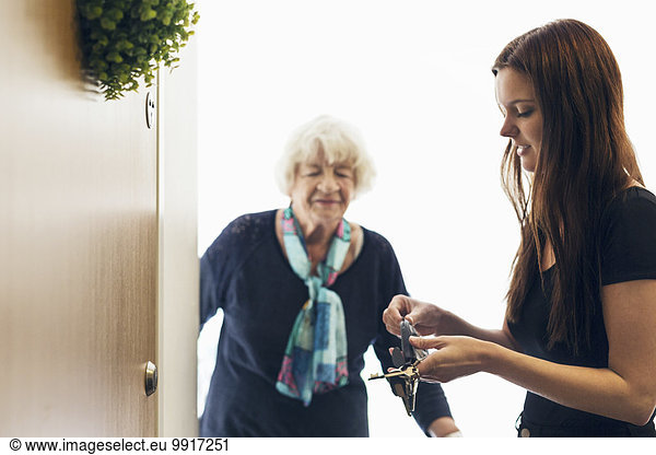 Ältere Frau schaut auf die Enkelin  die die Haustür öffnet