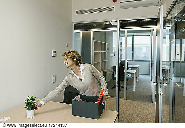 Ältere Geschäftsfrau ordnet Schreibtisch im Büro