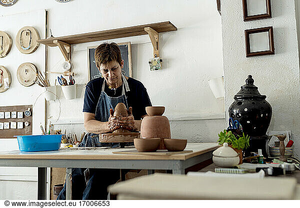 Ältere Künstlerin  die in einem Keramikladen aus braunem Ton töpfert