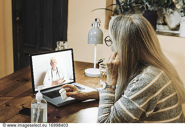 Ältere Patientin nimmt den Rat eines männlichen Arztes per Videoanruf während COVID-19 entgegen