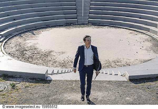 Älterer Geschäftsmann in einem Amphitheater auf einem stillgelegten Minenkippgelände