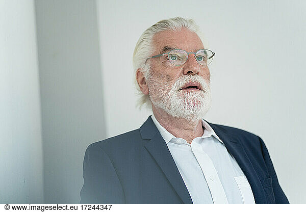 Älterer männlicher Berufstätiger mit Brille träumt im Büro