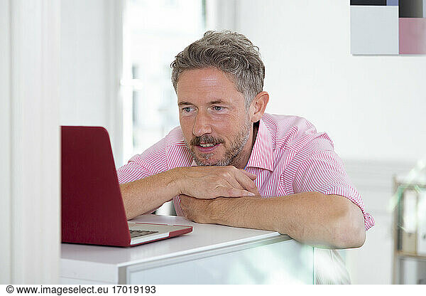 Älterer männlicher Berufstätiger mit Laptop am Schreibtisch