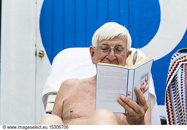 älterer Mann am Pool  liest ein Buch  älterer Mann liest ein Buch am Pool