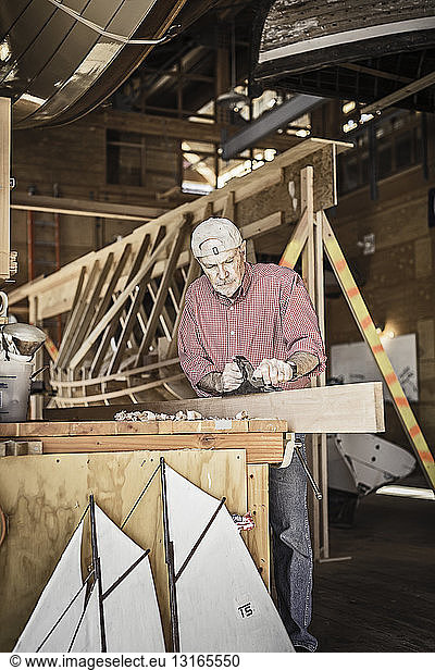 Älterer Mann  der sich mit Bootsbau-Hobby beschäftigt