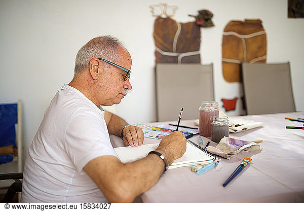 Älterer Mann malt Aquarell.