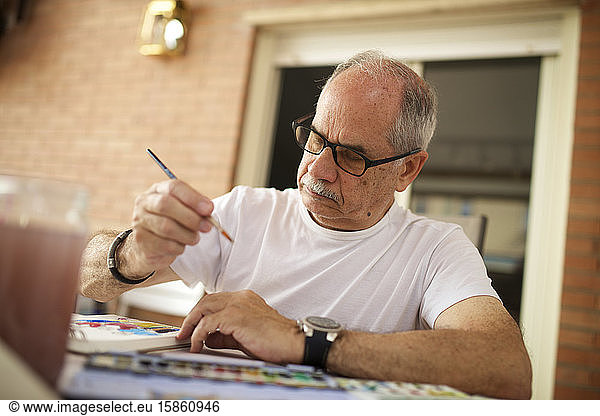 Älterer Mann malt Aquarell.