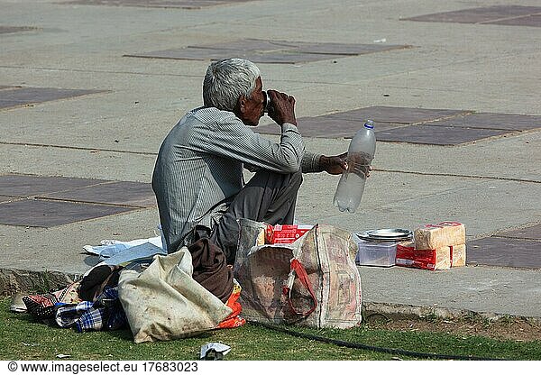 Älterer Mann sitzt am Straßenrand und trinkt Wasser  Rajasthan  Nordindien  Indien  Asien