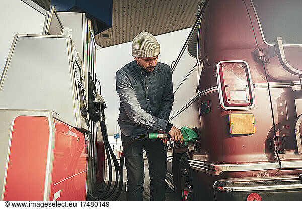 Älterer Mann tankt an einer Tankstelle Benzin in ein Wohnmobil