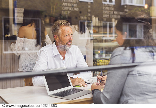 Älterer Mann und reife Frau unterhalten sich in einem Cafe