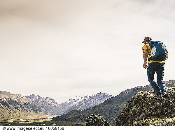 Älterer Wanderer mit Rucksack  der auf einem Felsen gegen den Himmel läuft  Patagonien  Argentinien