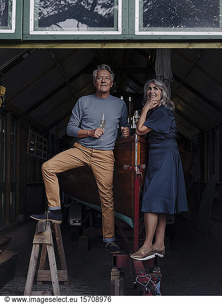 Älteres Ehepaar in einem Bootshaus mit einem Glas Champagner