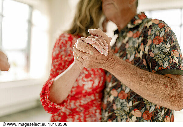 Älteres Paar hält sich an den Händen und tanzt zusammen im Unterricht