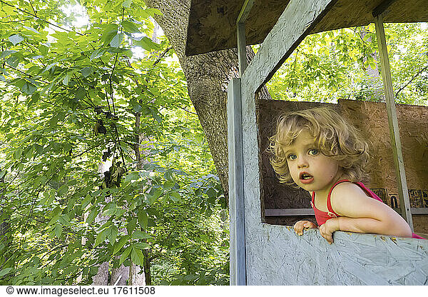 20 month old toddler girl relaxes in her backyard treehouse.; Cabin John  Maryland.