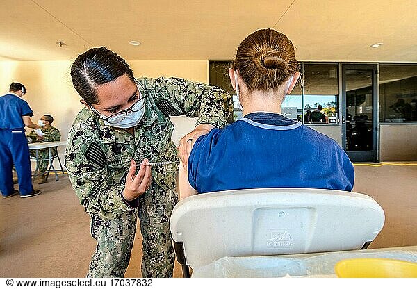 201215-N-VI515-2076.SAN DIEGO (15. Dezember 2020) Fire Controlman 2nd Class Jasmin Fiorini  eine dem Naval Medical Center San Diego (NMCSD) zugewiesene Matrosin  impft am 15. Dezember ein freiwilliges Dienstmitglied. Das NMCSD und das Naval Hospital Camp Pendleton (NHCP) wurden von der COVID Task Force des Verteidigungsministeriums ausgewählt  um die ersten Dosen des COVID-19-Impfstoffs von Pfizer zu erhalten. Die Auswahl erfolgte auf der Grundlage von Empfehlungen der militärischen Dienste und der US-Küstenwache  um mehrere Kriterien bestmöglich zu erfüllen  darunter die voraussichtlichen Anforderungen an die Lieferkette  wie z. B. Kühl- und Großlagereinrichtungen  eine lokale Bevölkerung von mindestens 1.000 vorrangig zu impfenden Personen aus allen militärischen Diensten und ausreichend medizinisches Personal  um die Impfstoffe zu verabreichen und die Impfstoffempfänger aktiv zu überwachen. Die Aufgabe des NMCSD besteht darin  Angehörige der Streitkräfte auf ihren Einsatz vorzubereiten  qualitativ hochwertige Gesundheitsdienstleistungen zu erbringen und die Zukunft der Militärmedizin durch Bildung  Ausbildung und Forschung zu gestalten. Das NMCSD beschäftigt in Südkalifornien mehr als 6.000 aktive Militärangehörige  Zivilisten und Vertragspartner  um Patienten jederzeit und überall eine erstklassige Versorgung zu bieten. (U. S. Navy Foto von Mass Communication Specialist 2nd Class Erwin Jacob V. Miciano).
